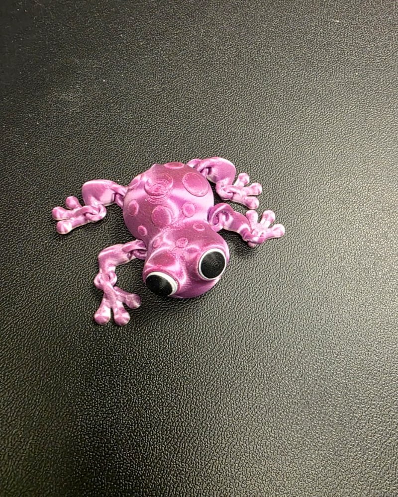 A pink and purple metallic articulated frog fidget toy with large eyes.