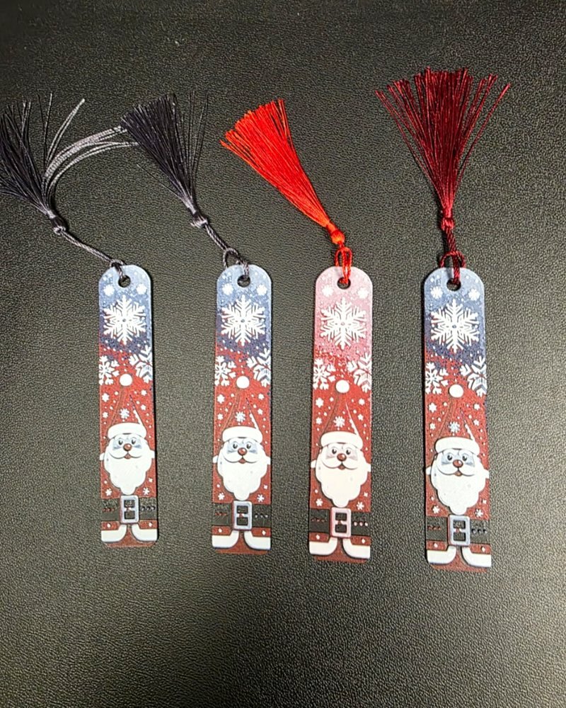 Four Christmas bookmarks with a printed Santa face and snowflakes, each with a colored tassel.