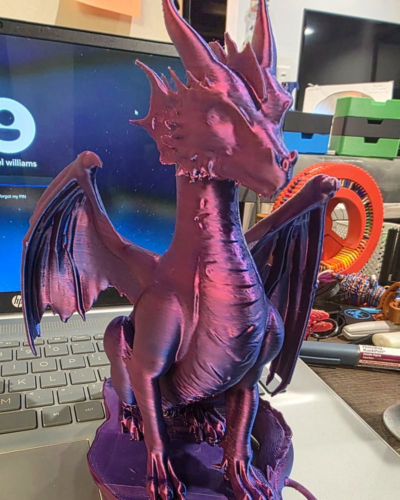 A large purple and pink color-shift dragon sitting on a rocky base with its wings half open.
