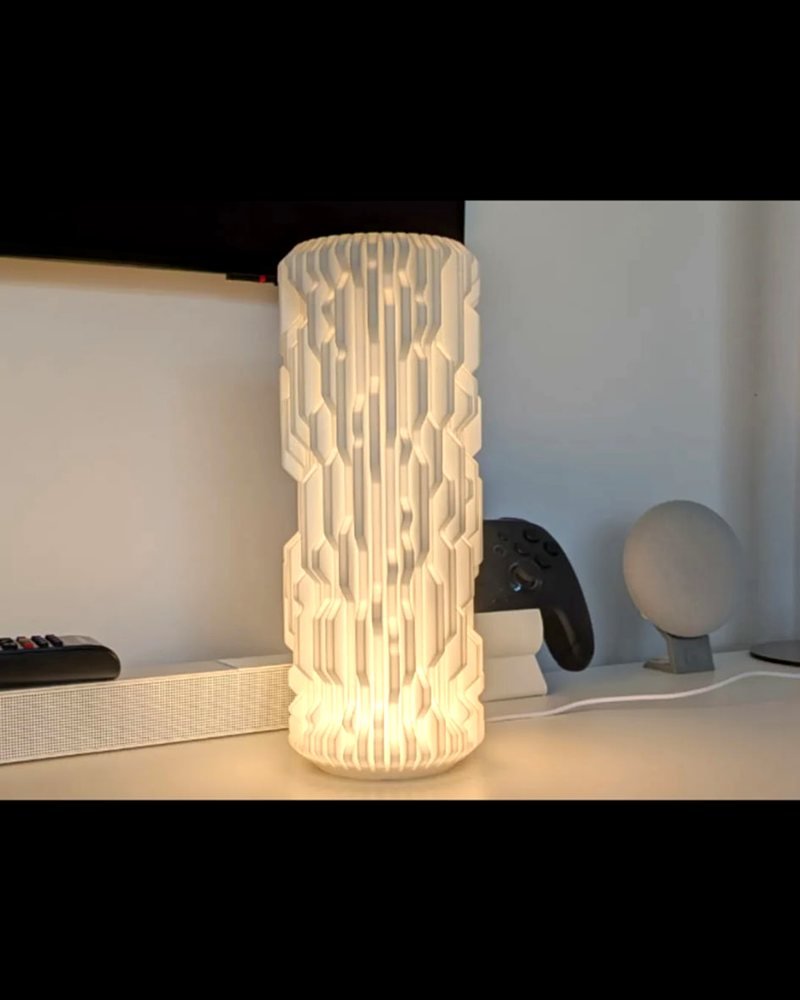 A tall white faceted cylindrical lamp shade glowing from an LED light inside.