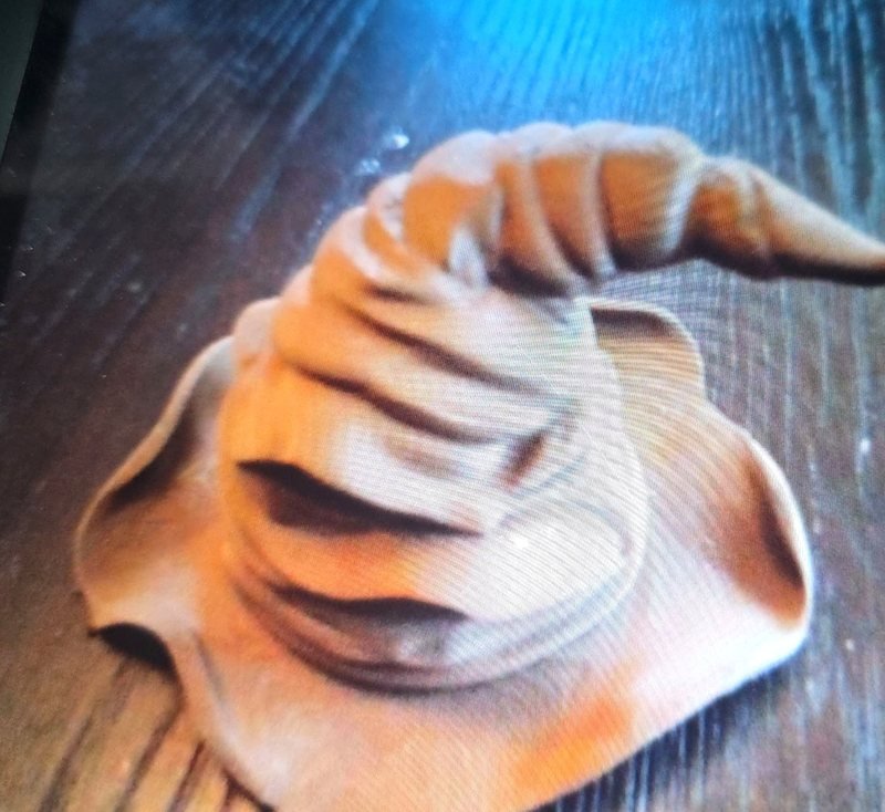 A wizard's pointed hat sculpture printed in wood-toned filament, sanded smooth so the layers read like wood grain.