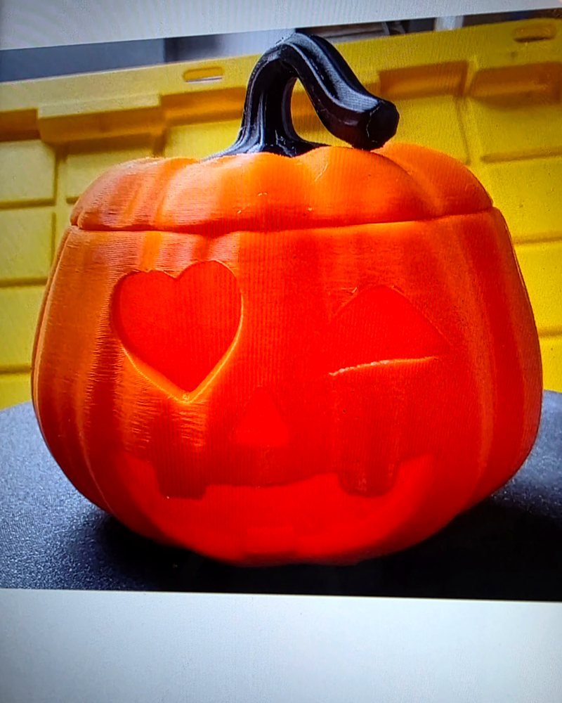 A short round orange jack-o'-lantern with a heart-shaped eye, triangle nose, and black stem.