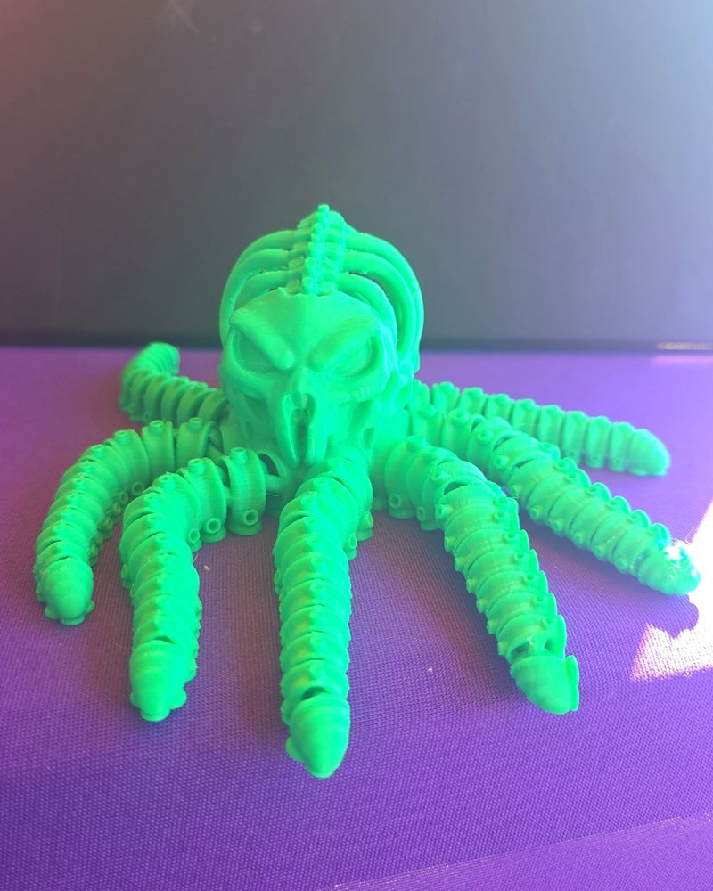 A bright green articulated octopus with a skull-shaped head and eight segmented tentacles.