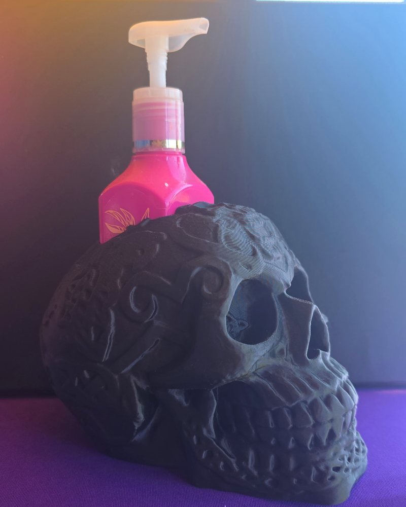 A black carved skull with a pink soap bottle sitting behind it.