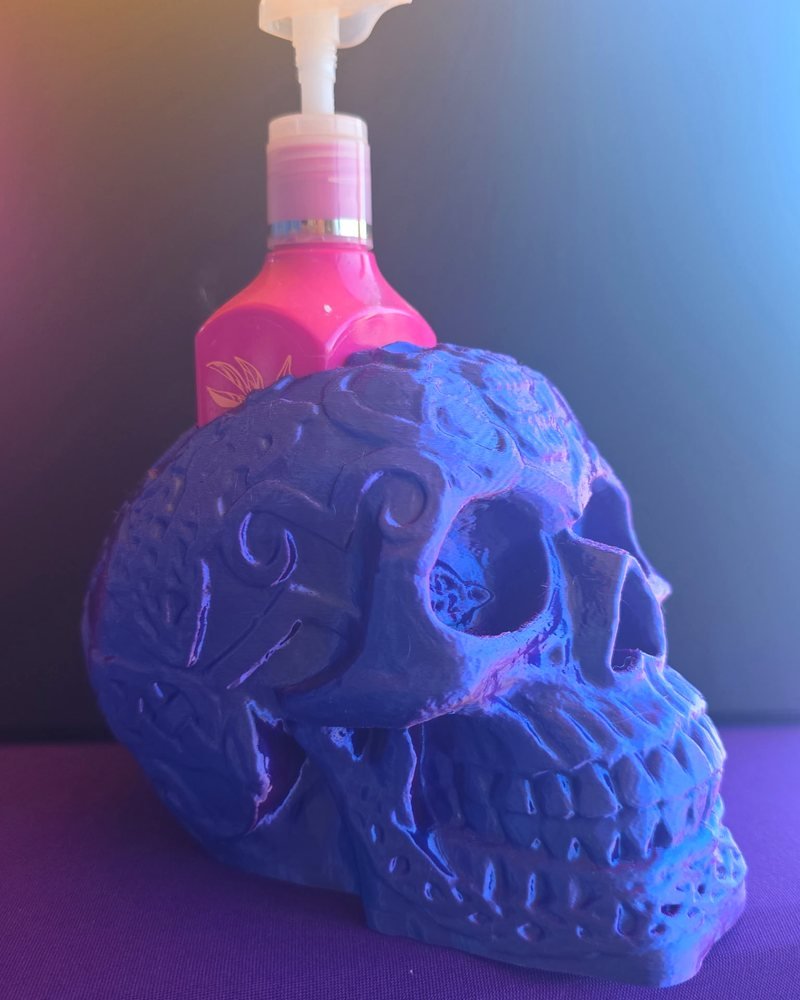 A blue and purple carved skull with a pink soap bottle sitting behind it.