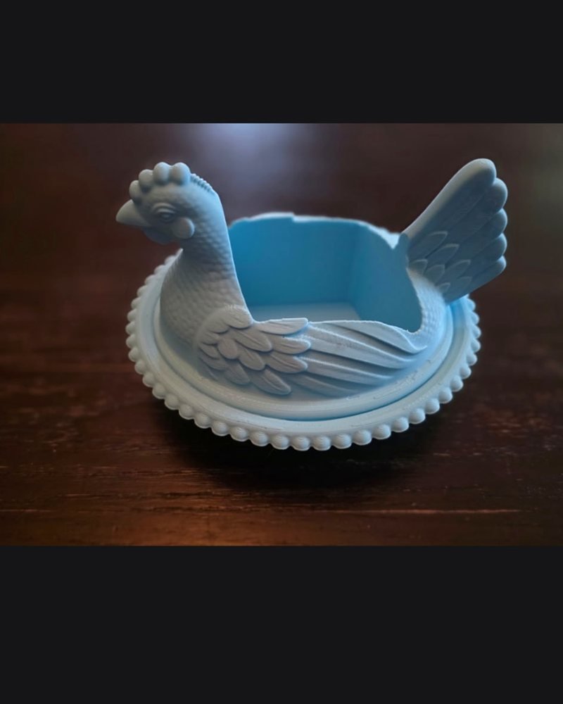 A light blue hen-shaped bowl, smaller version, on a wood table.