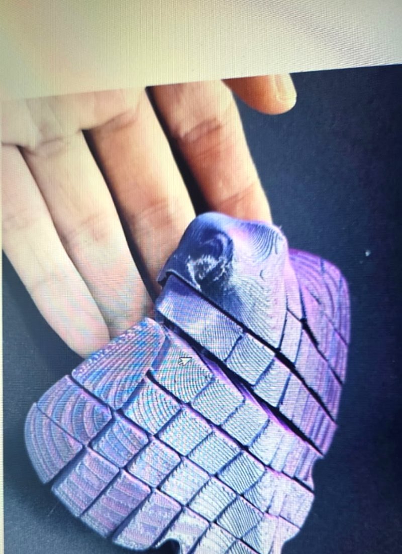A purple metallic articulated stingray figurine, shown flexed in a hand.